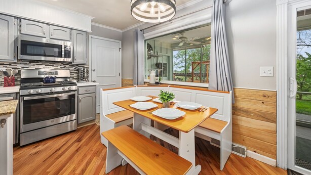 A modern kitchen with stainless steel appliances, a wooden dining table, and a bench. - Sandstone Hollow | King Suite, Office, Fenced Yard (Fort Collins)