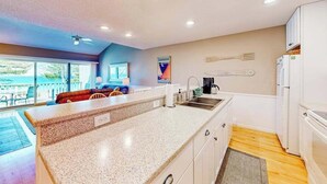 A kitchen with a granite countertop, white cabinets, a built-in sink, and a refrigerator. - Waterfront condo near skiing with beach access, on-site golf & fireplace (Glen Arbor)