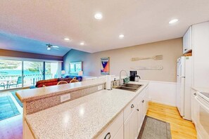 A kitchen with a granite countertop, white cabinets, a built-in sink, and a refrigerator. - Waterfront condo near skiing with beach access, on-site golf & fireplace (Glen Arbor)