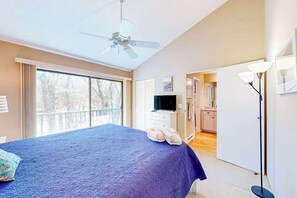 A bedroom with a bed, a ceiling fan, a TV, and a view of the outdoors. - Waterfront condo near skiing with beach access, on-site golf & fireplace (Glen Arbor)
