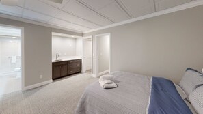 A bedroom with a bed, a bathroom with a shower, and a kitchen area. - Stylish retreat with a full kitchen, sunroom, & W/D access (Glen Arbor)