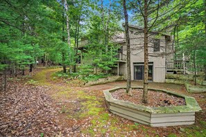 A cabin with a deck, surrounded by a forest. - Two-story home with a patio, sunroom, balcony, & washer/dryer access (Glen Arbor)