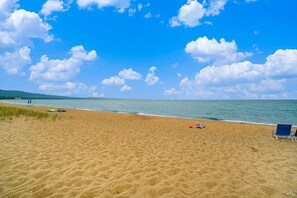 A sandy beach with a clear blue sky and a calm sea. - Lake-view condo with private beach, fireplace, deck, washer/dryer, streaming (Glen Arbor)