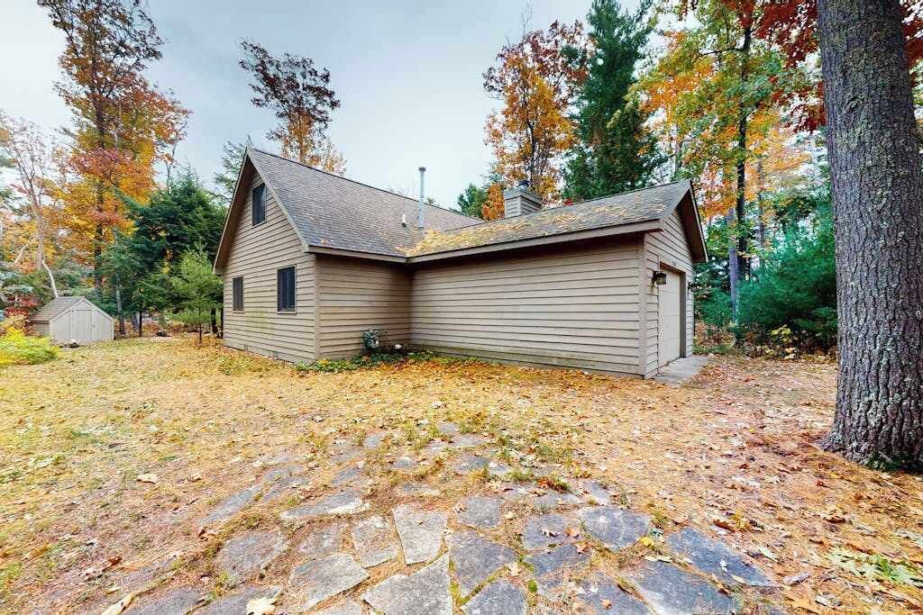 Ein einstöckiges Haus mit einer gepflasterten Auffahrt, umgeben von Bäumen mit Herbstlaub.