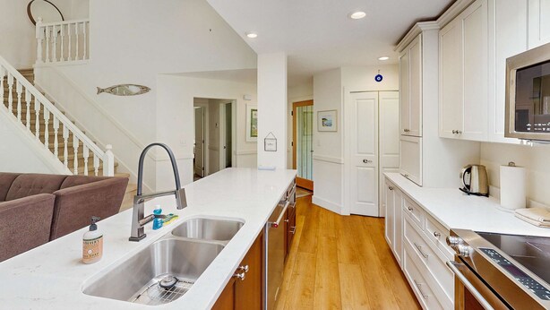 Una cocina moderna con una isla grande, electrodomésticos de acero inoxidable y una escalera de madera.