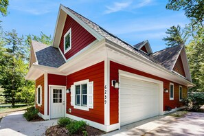 Une maison à deux étages, avec une façade rouge, des boiseries blanches et une porte de garage.