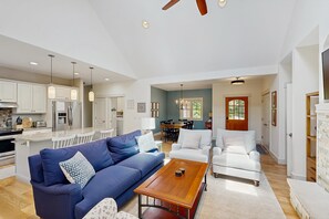 A spacious living area with a blue sofa, a wooden coffee table, and a striped armchair. - Downtown home near the lake with washer/dryer, firepit, backyard (Glen Arbor)