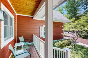 A wooden porch with a railing, two chairs, and a small table. - Downtown home near the lake with washer/dryer, firepit, backyard (Glen Arbor)
