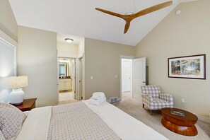 Une chambre d’hôtel avec un lit, une chaise, une petite table ronde, un ventilateur de plafond et un tableau au mur.