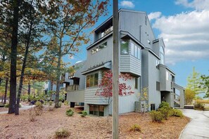 Un bâtiment moderne à plusieurs étages, doté d’une architecture originale, entouré d’arbres et s’ouvrant sur un ciel dégagé.