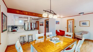 Ein Essbereich mit einem Holztisch, weißen Stühlen, einer Kandelaber und einer Küche im Hintergrund.
