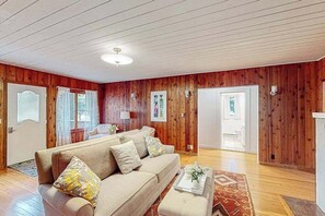 A cozy living room with a sofa, a coffee table, and a patterned rug. - Dog-friendly downtown Glen Arbor home with deck, gas grill, and washer/dryer (Glen Arbor)