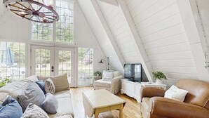 Une pièce de style loft avec un plafond en pente, une télévision, une petite table et un canapé.
