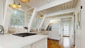 Une cuisine avec des meubles blancs, un îlot central et un plancher en bois.