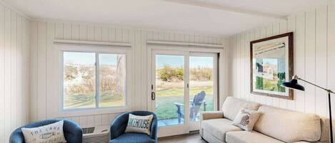 A living room with a sofa, two armchairs, a coffee table, and a large window with a view of the outdoors.