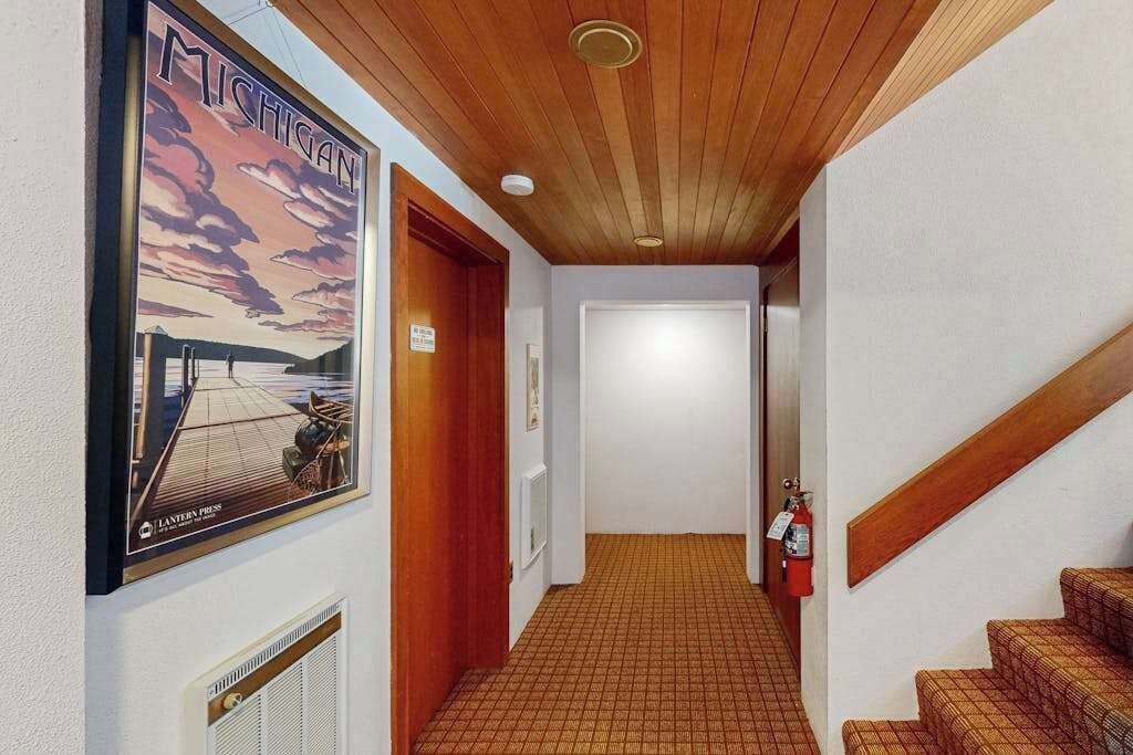 A hallway with a wooden ceiling, a fire extinguisher, and a poster on the wall.