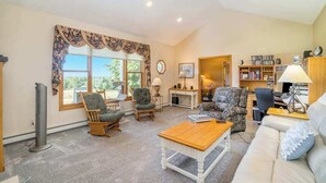 Una sala de estar con chimenea, una estantería y una ventana con cortinas.
