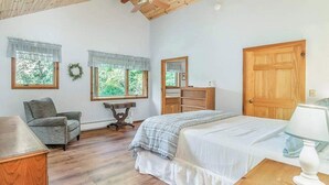 A bedroom with a bed, a chair, a dresser, a mirror, and two windows with curtains. - Peaceful, two-story home with a firepit & washer/dryer - close to the beach (Empire)
