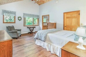 A bedroom with a bed, a chair, a dresser, a mirror, and two windows with curtains. - Peaceful, two-story home with a firepit & washer/dryer - close to the beach (Empire)