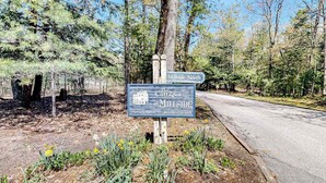 A sign for 'The Cottages at Millside North' with a private road and wooded area. - Riverfront condo with lake access, views, deck, washer/dryer, community firepit (Glen Arbor)