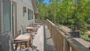 A wooden deck with outdoor seating, a wooden railing, and a view of trees. - Spacious lake access home with a washer/dryer, central AC, nearby tennis (Glen Arbor)