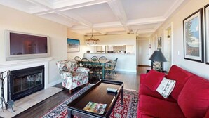 Un salon avec une cheminée, un canapé rouge, une table basse et un coin repas avec des chaises et une table.