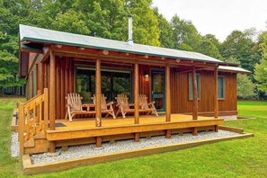 A wooden cabin with a porch, outdoor seating, and a chimney.