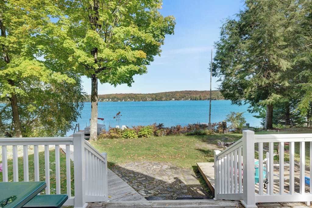 A wooden deck leading to a lake with a clear view of the water and distant land.