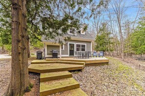Une maison à deux étages dotée d’une terrasse, d’un barbecue et d’un patio avec des meubles d’extérieur.