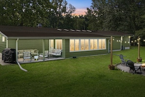 A house with a covered patio, outdoor seating, and a lawn.