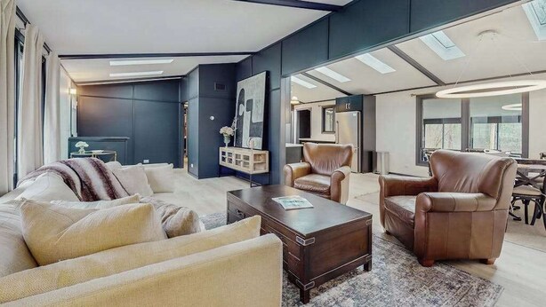 Un salon moderne comprenant un canapé, des fauteuils, une table basse et un coin repas avec une table et des chaises.