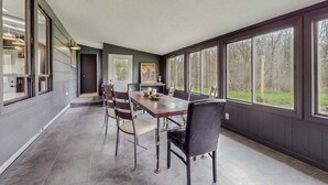 Un vaste espace dédié à la salle à manger, avec une longue table et des chaises, de grandes fenêtres et une vue sur l’extérieur.