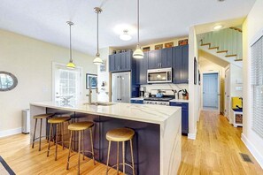 A modern kitchen with a central island, bar stools, and pendant lighting. - Newly-updated grand home in Union Pier‚Äôs Lakeshore Cottages with pool (Union Pier)