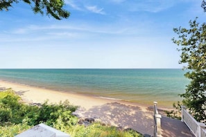 A beach with a wooden deck and a clear view of the ocean. - Rustic beach cottage with partial lake views, grill, & WiFi - great location (Michiana)