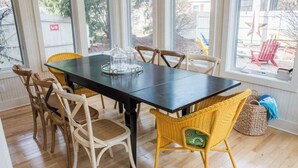 Un coin repas avec une table en bois foncé, des chaises en osier et une vitrine.