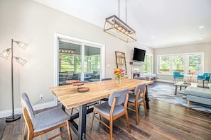 A dining area with a wooden table, grey upholstered chairs, and a hanging light fixture.