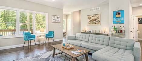 A spacious living room with a large grey sofa, a coffee table, and two blue chairs.