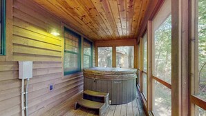 Eine Holzhütte mit Whirlpool, einem Fenster und einer Stufe zum Whirlpool.