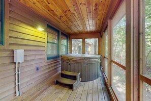 Een houten chalet met een hottub, een raam en een trap naar de hottub.