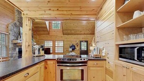 Ein Interieur einer Holzhütte mit einer Küche, die einen Herd, einen Backofen und eine Mikrowelle beinhaltet.