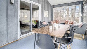 En modern inredning med ett matbord i trä, grå klädda stolar och en soffa med mönstrade kuddar.