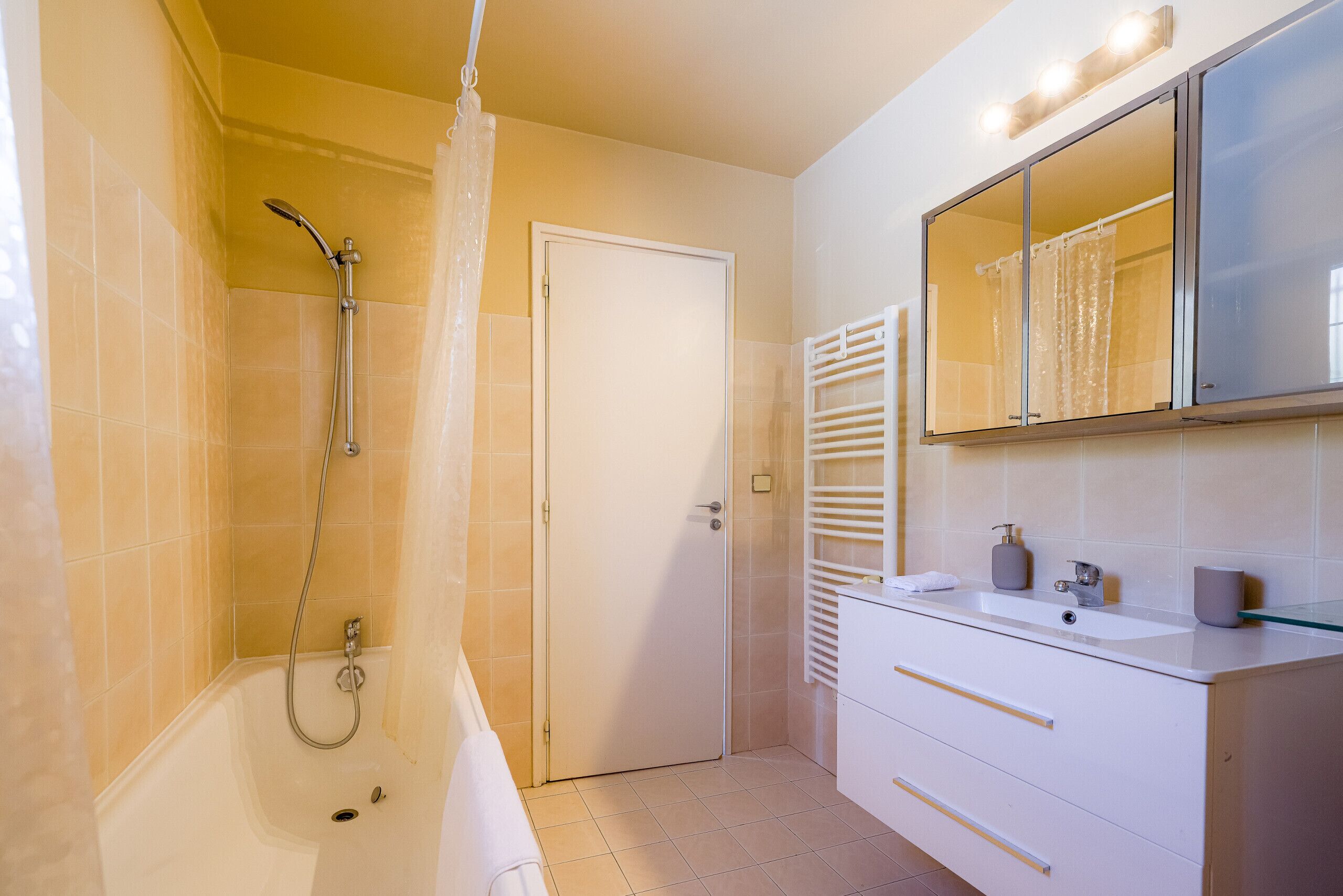 A bathroom with a bathtub, a shower, a toilet, a sink, and a mirror.