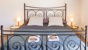 A bed with a metal frame, two pillows, a blanket, and two bedside lamps. - Le Pioulier – Villa in Vence with an open view (Vence)