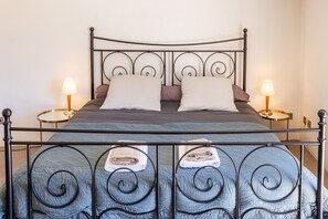 A bed with a metal frame, two pillows, a blanket, and two bedside lamps. - Le Pioulier – Villa in Vence with an open view (Vence)