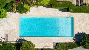 An aerial view of a rectangular swimming pool with a stone border, surrounded by greenery and a stone pathway. - Le Pioulier – Villa in Vence with an open view (Vence)