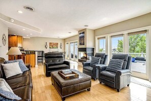 A spacious living room with leather sofas, a fireplace, and large windows. - Riverfront Home w/Private Deck/River Views/Free WiFi - Near Restaurants/Marina (Saugatuck)
