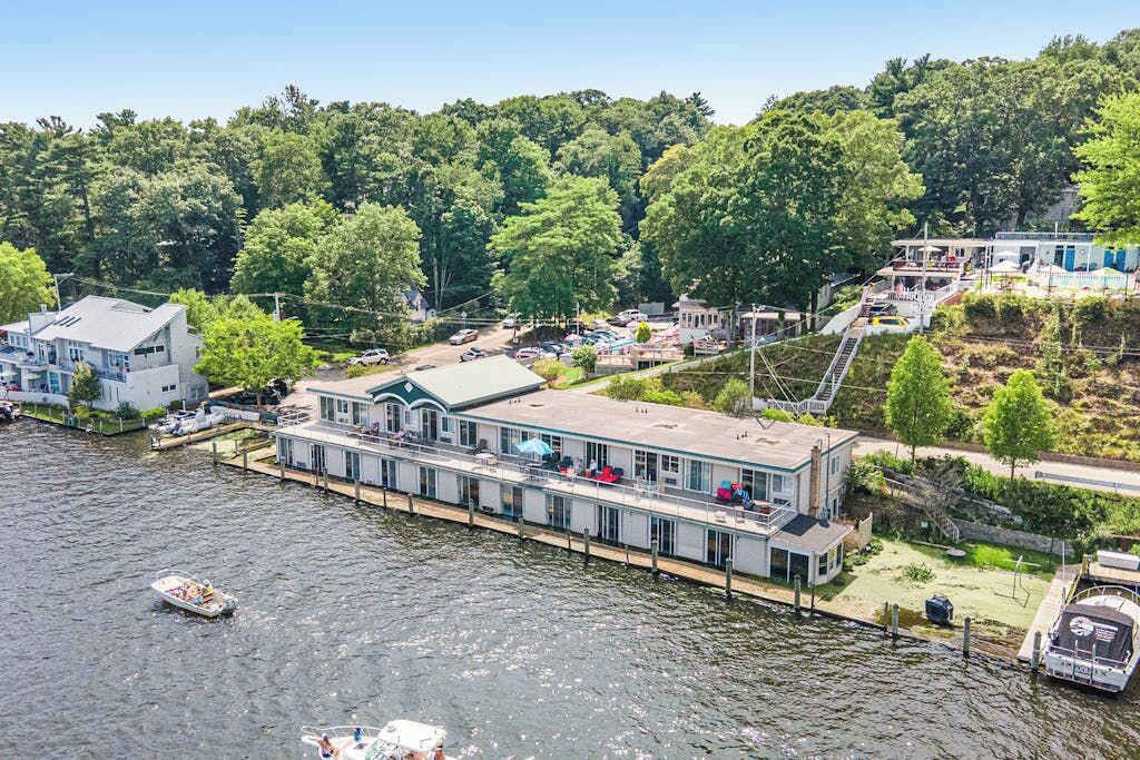 A waterfront property with a dock, a boat, and a building with a covered deck.