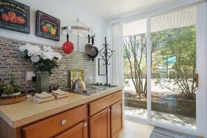 A kitchen with a brick backsplash, a large window, and a view of trees.