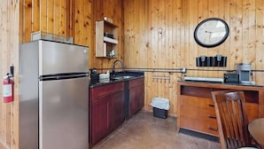 A compact kitchen with wooden walls, a stainless steel refrigerator, a sink, and a clock. - Peaceful wooded escape w/ kitchenette, gas grill, WIFI, lakes & trails nearby (Covert)
