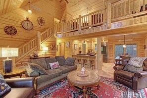 A spacious wooden cabin with a loft, a dining area, and a bar.